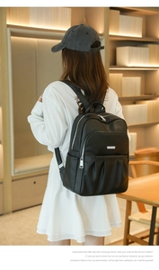 Detail of black pebbled leather backpack with pleated front pocket on a model's back