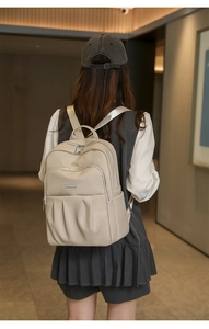Detail view of beige ruched leather backpack showing textured finish and silver hardware