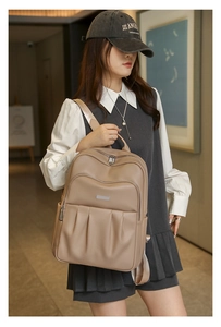 Detail of khaki pebbled leather backpack showing pleated pockets and silver metal zippers