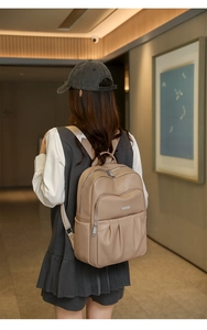 Close-up of a khaki leather backpack featuring silver zippers and pebbled texture detail
