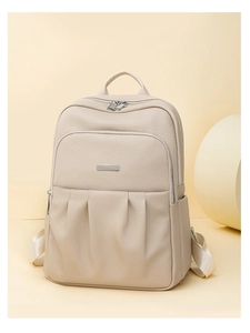 Detail of beige Oxford cloth backpack showing litchi grain texture and silver metal plate