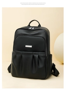 Detail of black pebbled leather backpack with silver zippers and vertical pleat design