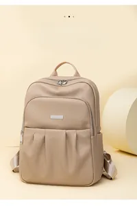 Detail of beige lychee textured backpack with silver zippers and pleated front pockets