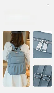 Detail view of light blue oxford backpack featuring silver zippers and adjustable straps