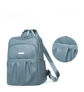 Detail display of grey-blue oxford backpack with pleated design and silver hardware