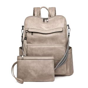 Close-up of khaki faux leather backpack and wristlet set with tassel detail