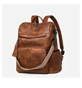 Detail view of brown faux leather backpack with woven strap and tassel accent