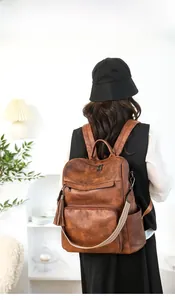 Rear view of vintage brown leather backpack for women with tassels on minimalist background
