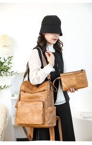 Detail view of vintage caramel leather backpack and matching clutch with tassel charm