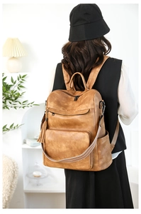 Detail view of brown vintage laptop backpack with tassel and woven shoulder strap