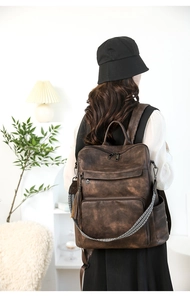 Detail of vintage brown leather backpack with tassel charm and woven shoulder strap