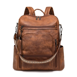Detail view of brown PU leather backpack showing ethnic woven strap and tassel charm