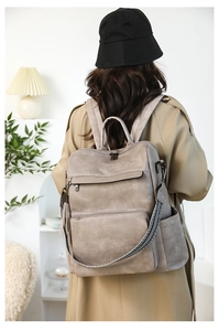 Taupe vintage-style women's backpack featuring striped straps and tassel charm in a home setting