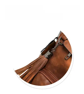 Detail view of smooth zipper and stylish fringe tassel on brown leather laptop backpack