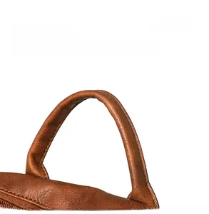 Macro detail of ergonomic brown leather top handle with soft rounded grip and fine texture