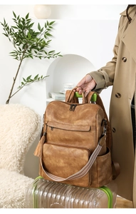 Brown vintage leather backpack detail featuring long tassel zipper and ethnic woven strap