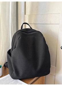 Detail eines schwarzen Mesh-Rucksacks mit Seitentasche auf einer Holzoberfläche