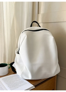 Detail eines weißen Netzrucksacks mit schwarzen Griffen und Seitentasche auf Holzfläche