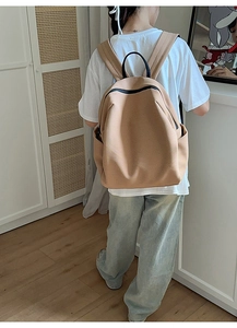 Detailansicht des beigen Canvas-Rucksacks mit schwarzen Reißverschlüssen am Modell