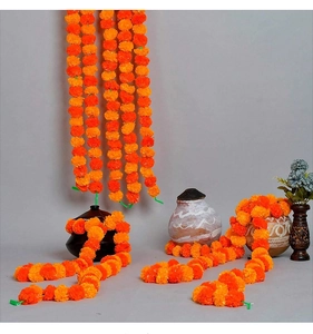 Vibrant orange marigold garland detail draped on vintage pots for festive decor