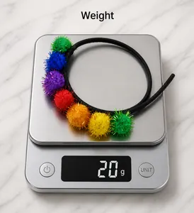 Gros plan d'un serre-tête à pompons colorés et pailletés pesant 20g sur une balance