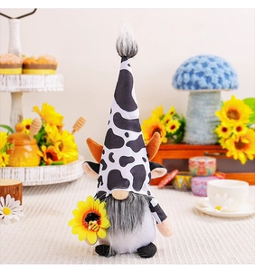 Détail d'un gnome en peluche motif vache tenant un tournesol avec une petite abeille
