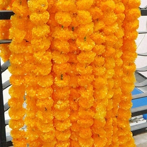 Artificial orange marigold flower garlands hanging on a black metal fence for festivals