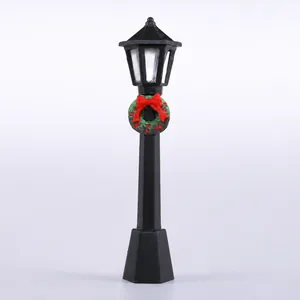 Farola vintage en miniatura negra con lazo rojo y corona de Navidad decorativa