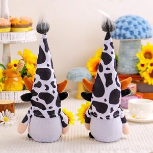 Vue arrière de deux gnomes en peluche motif vache avec tournesols et décor rustique