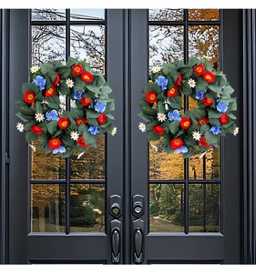 Close-up of patriotic red blue and white floral wreaths hung on a black front door
