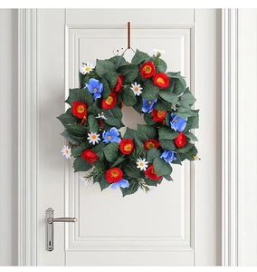 Close-up of artificial wreath with red and blue flowers on a white wooden door decor