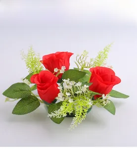 Detail of red silk rose candle ring with small white flowers and green artificial foliage