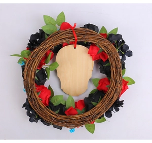 Dettaglio di rose rosse e nere su ghirlanda di rattan con una targa in legno a teschio