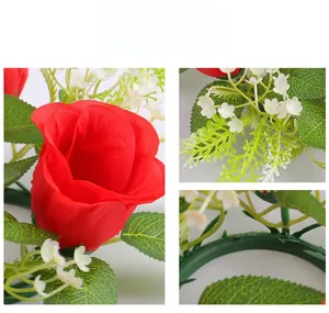 Detailed close-up of red artificial rose candle ring with realistic fabric petals and green leaves