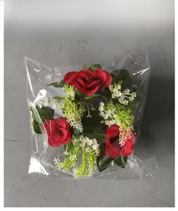 Top view of artificial red rose wreath with white flowers in clear plastic packaging