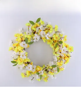 Detail of handmade artificial spring wreath with yellow and white flowers on white background