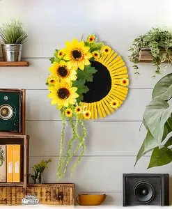 Détail d'une couronne de tournesols avec pinces en bois sur un mur en bois blanc