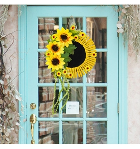 Détail de couronne de tournesols avec pinces en bois sur une porte bleue