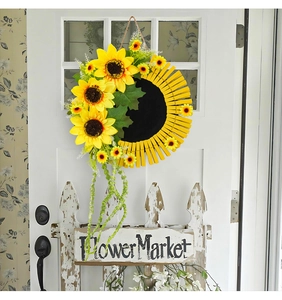 Détail de couronne de tournesol avec pinces en bois et silhouette sur une porte blanche