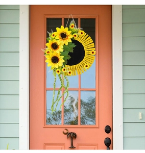 Détail d'une couronne de tournesols avec pinces en bois sur une porte rose élégante