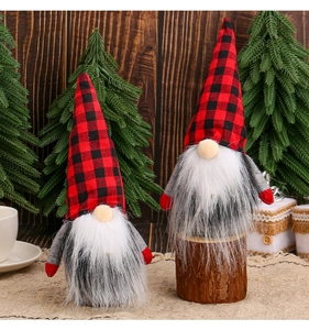 Detail of two Christmas gnomes with red and black buffalo plaid hats on wood background