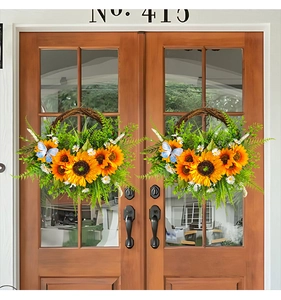 Detail of two sunflower wreaths with blue butterfly accents hanging on a wooden door