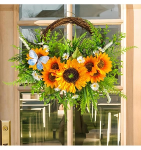 Detail of vibrant sunflower wreath with white daisies and blue butterfly on wooden door
