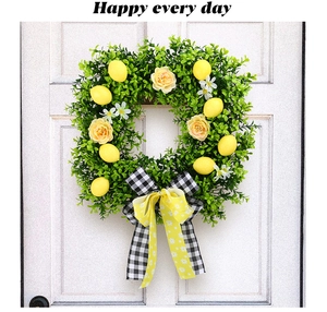 Close-up of artificial lemon wreath with green leaves and yellow bow on white door