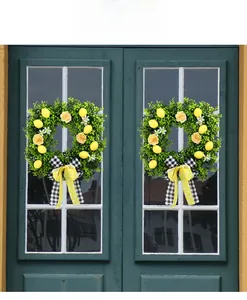 Close-up of artificial lemon wreaths with yellow roses and bows on green glass doors