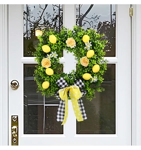 Close-up of artificial lemon wreath with yellow roses and daisy ribbon on white door
