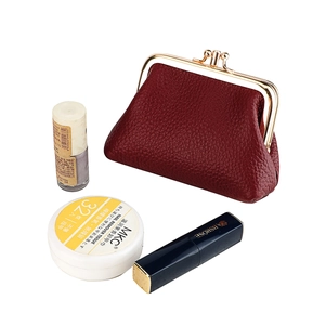 Detail of red pebbled leather coin purse with gold kiss-lock closure and cosmetic items