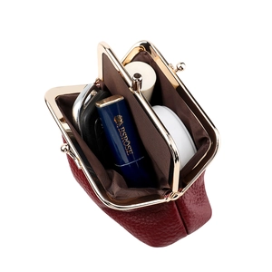 Macro view of burgundy pebble leather coin purse showing two compartments with accessories