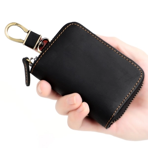 Detailed view of black leather car key case with orange stitching and vintage bronze clip