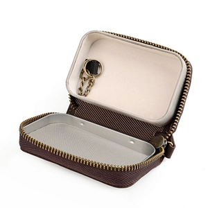 Detail of open brown car key case with brass zipper and internal metal tray storage